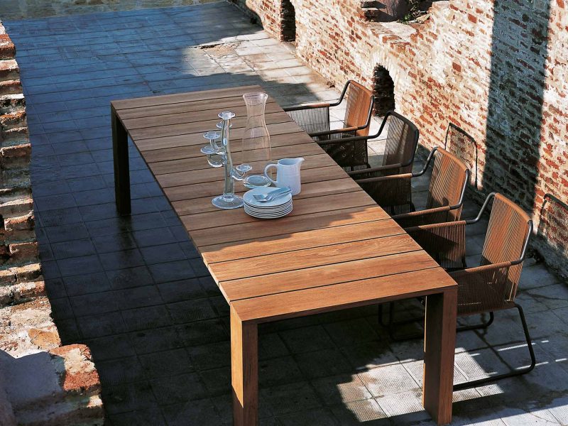 Großer Gartentisch mit Stühlen steht im Schatten einer Veranda