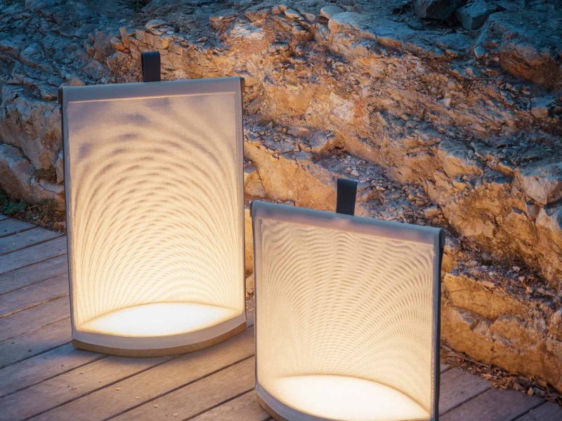 Laternen mit Licht stehen auf einer Holzterrasse in der Dämmerung